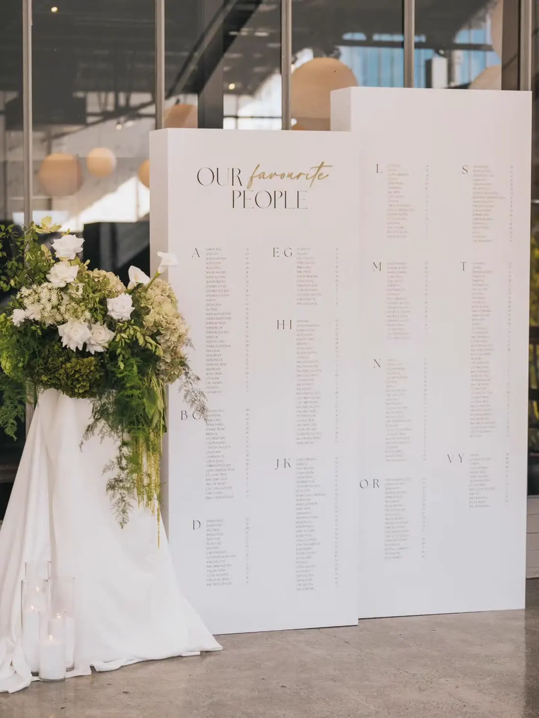 Tall white seating chart panels styled with florals and candles